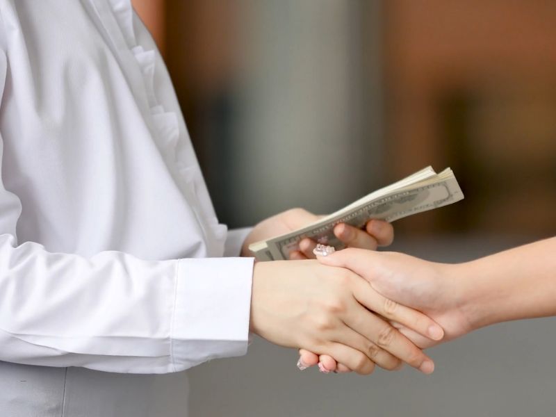 osoba predaje drugoj osobi novac i rukuju se